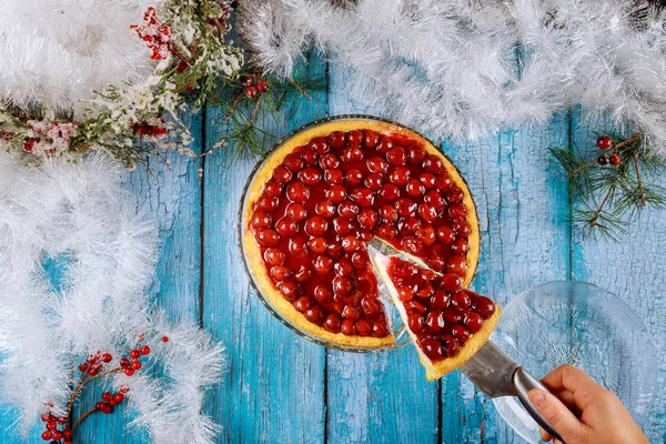 Frau hält Stück Kirschtorte auf Tisch mit Weihnachtsdekoration. — Stockfoto