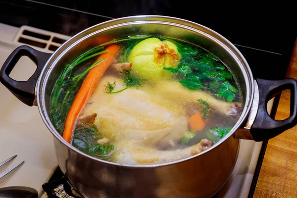 Chicken broth with carrots, whole chicken, onion, celery and parsley. — Stock Photo, Image