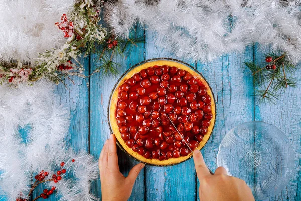 Frauenhände schneiden Kirschtorte auf blauem Holztisch. — Stockfoto