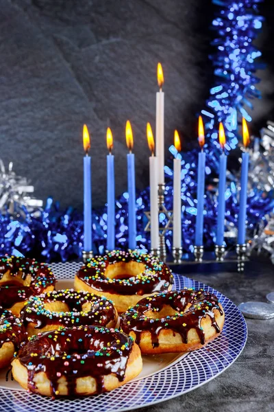 Jewish holiday Hanukkah. Sweet donuts and menorah with burning candles.
