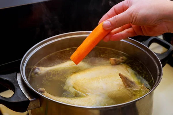 Γυναικείο χέρι βάζει καρότο στην κοτόσουπα. — Φωτογραφία Αρχείου