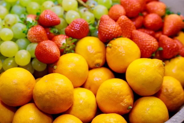 Čerstvé ovoce. Tangerinky a jahody s hrozny v měkkém zaostření. — Stock fotografie