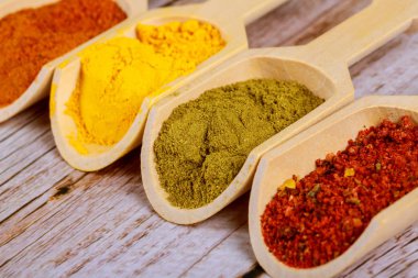 Tahta kepçelerde dört farklı baharat. Paprika tozu, köri, hardal ve baharat..