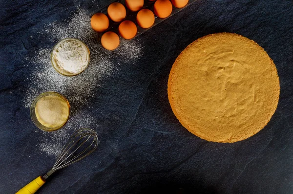 Ingredientes para bolo de esponja. Bolo pronto no fundo preto . — Fotografia de Stock