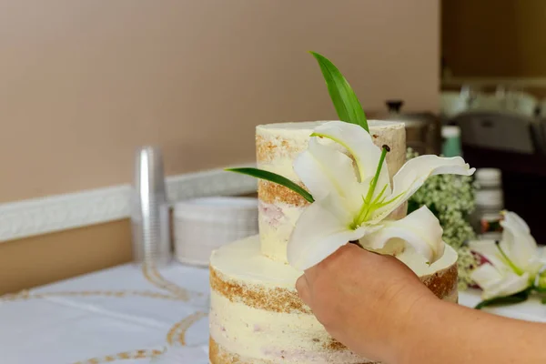 Woman decorating naked cake with flowers. — Stock Photo, Image