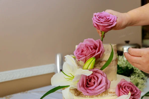 Woman decorating naked cake with flowers. — Stock Photo, Image