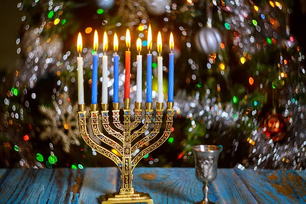 Hanukkah bord med menorah och brinnande ljus på glitter bakgrund med defocused färgade lampor. — Stockfoto