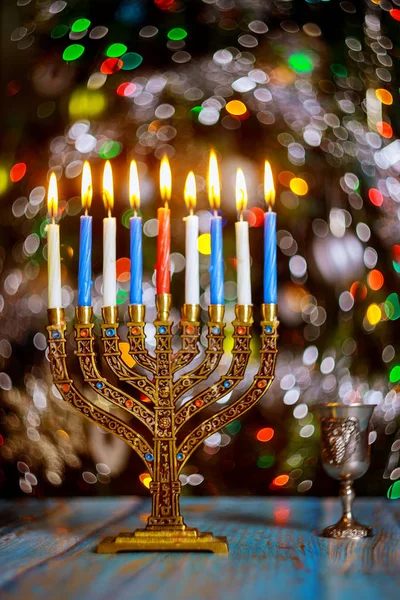 Mesa Hanukkah com menorah e velas acesas no fundo cintilante com luzes coloridas desfocadas . — Fotografia de Stock