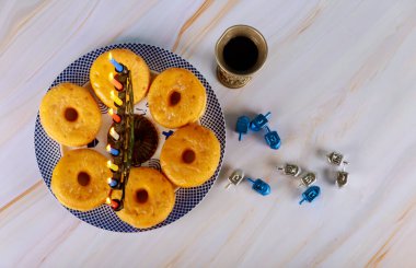 Hanuka menorası ve tabakta şarap ve dreidel ile donut..