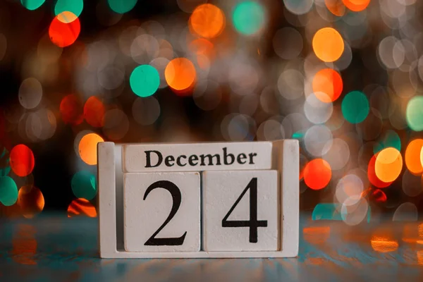 Houten kubus met kerstboom verlichting achtergrond. Kerstavond concept. 24 december. — Stockfoto