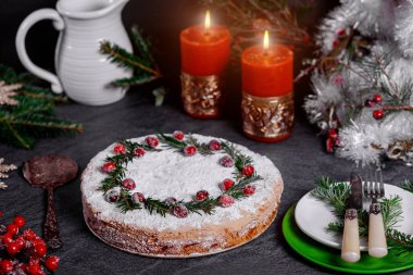 Yaban mersini ve çam dallarıyla süslenmiş Noel pastasıyla.