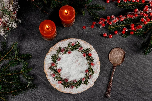Festlicher Weihnachtskuchen mit Cranbarry-Dekoration auf schwarzem Tisch mit brennenden Kerzen. — Stockfoto