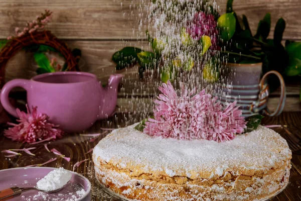 Saupoudrer de sucre sur le gâteau avec des fleurs . — Photo