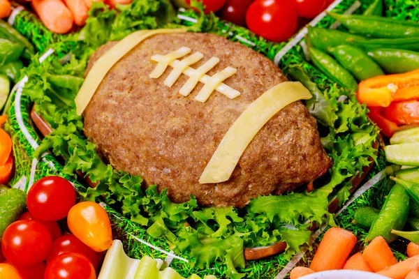 Bandeja de verduras saludables con pastel de carne como una pelota de fútbol para la fiesta de fútbol americano. De cerca. . —  Fotos de Stock