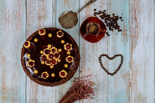 Torta di ciliegie con glassa al cioccolato, tazza di caffè e fiori . — Foto Stock