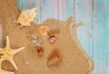 Deniz kabuklu denizyıldızı mavi ahşap arka planda deniz kumu. Mantarlı cam şişedeki papirüs..