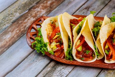 Tahta arka planda et, fasulye ve sebzelerle doldurulmuş un tortilla..