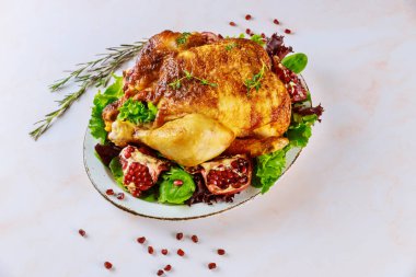Roasted turkey on plate with herbs and pomegranate.