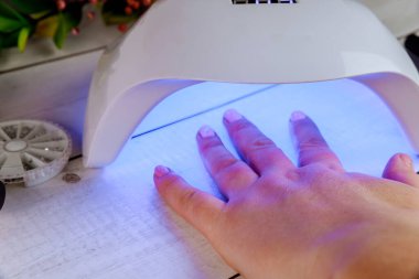 Kadın akrilik manikür yapmak için Led Lambası 'na elini sokuyor..