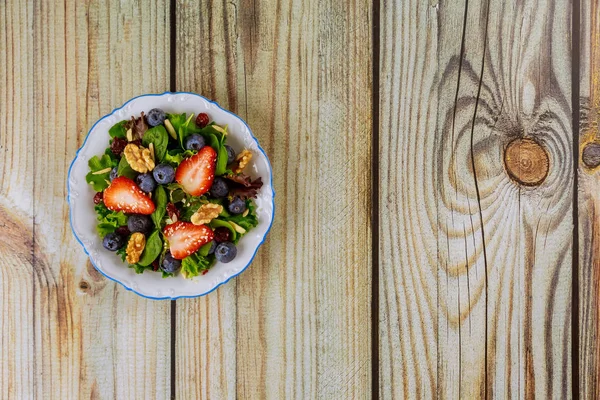 Delisious spinach salad with strawberry, walnuts and sesame seeds.