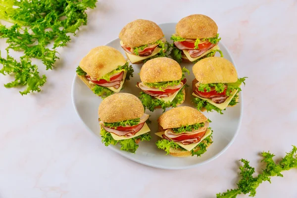 Pequenos sanduíches com presunto e queijo na placa na mesa de madeira . — Fotografia de Stock