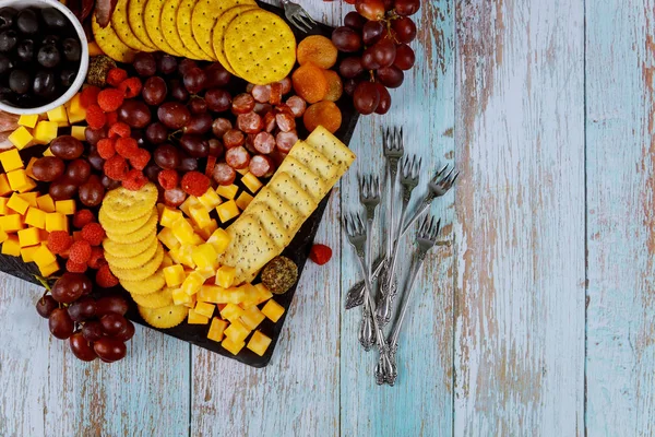 Картонная доска с сыром, виноградом, редиской и кракерами . — стоковое фото
