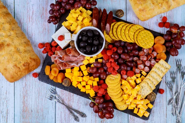 Surtido de tablas de charcutería, queso, aceitunas, frutas y jamón sobre mesa de madera . — Foto de Stock