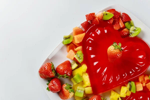 Gelatina de fresa en forma de corazón decorada con fresa fresca, kiwi y piña. Postre para pareja . —  Fotos de Stock