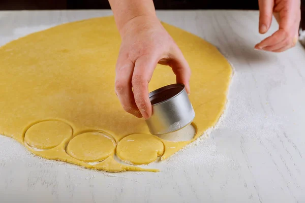 Mujer corta masa para hornear galletas en la mesa . — Foto de Stock