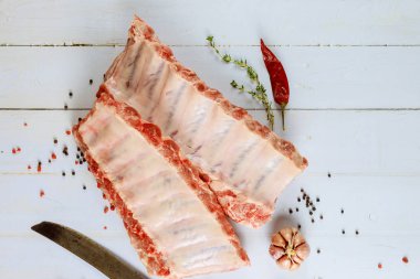 Raw beef ribs with herbs, garlic and pepper on white background.