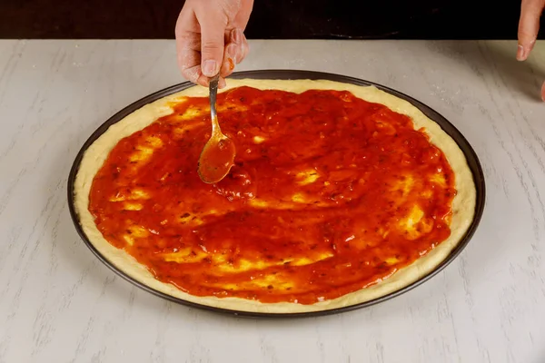 Séf fedezi nyers pizza tészta mártással. — Stock Fotó