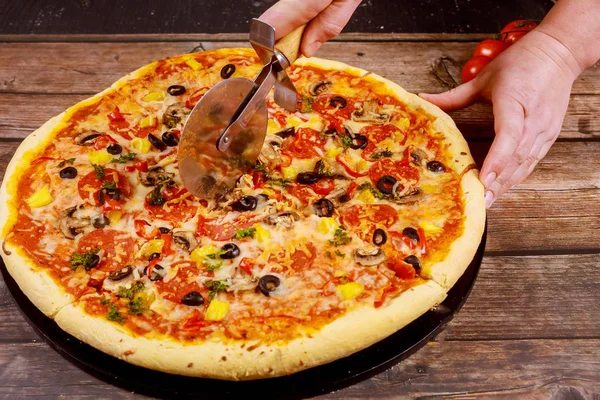 Chef cut pizza with cutter on wooden background. — Stock Photo, Image