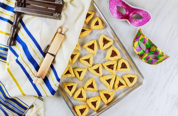Biscotti ebraici Orecchie di Haman in teglia per Purim con maschera, tallit e rumorista . — Foto Stock