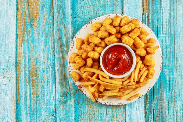 Classic french fries and tasti taters with ketchup on wooden table. — ストック写真