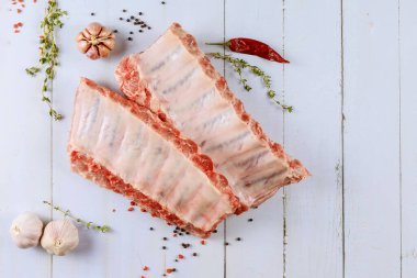 Raw lamb ribs with herbs, garlic and pepper on white background.