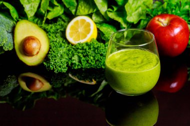 Fresh vegetable smoothie with ingredients on black background.