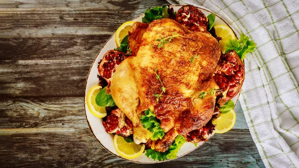 Celé pečené kuře na talíři se salátem a granátovým jablkem. — Stock fotografie