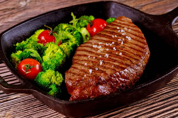 Grillowany średnio wysmażony stek wołowy z brokułami i pomidorami na patelni. — Zdjęcie stockowe
