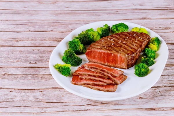 Sliced rare beef tenderloin with broccoli on white plate. — Stock Photo, Image