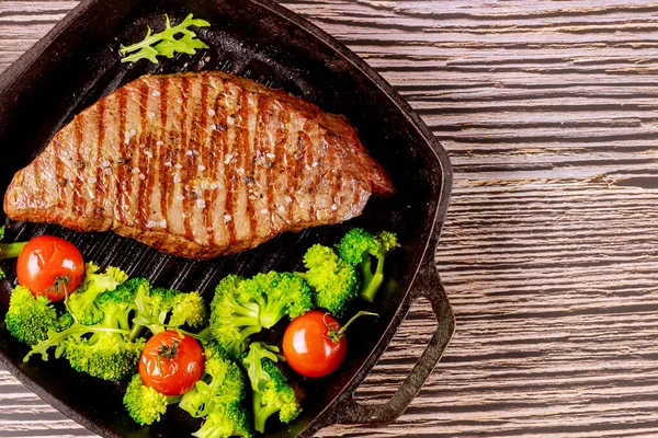 Grilled rare beef steak with broccoli and tomato on grill pan. — Stock Photo, Image