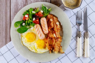Kahvaltı için nefis yemek yumurta, sosis, pastırma, çatallı salata ve bıçak..