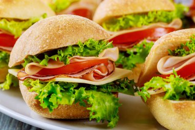 Jambon, peynir, marul ve domatesli ciabatta rulosundan yapılmış lezzetli sandviçler. Kapat..