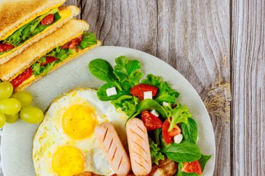 Domuz eti, kızarmış yumurta, ızgara peynirli sandviç ve kahvaltıda salata..