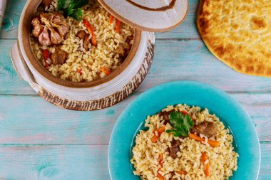 Özbek pilavı, pirinç, et, havuç ve sarımsak ile kil çömlek içinde düz ekmek.