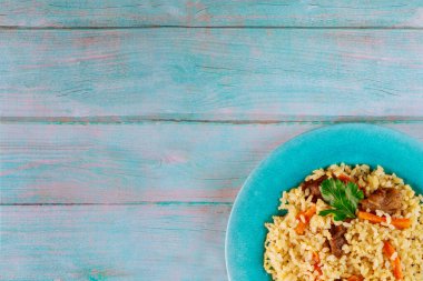 Sebzeli Asya pirinci ve ahşap zemin üzerinde mavi tabakta et..