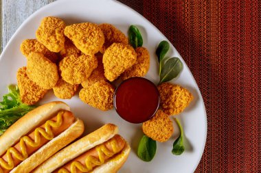 Ketçaplı tavuk nugget ve beyaz tabakta hardallı sosisli sandviç. Fast food konsepti.