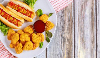 Ketçaplı tavuk nugget ve beyaz tabakta hardallı sosisli sandviç. Fast food konsepti.