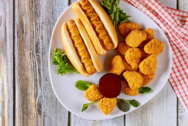 Ketçaplı tavuk nugget ve beyaz tabakta hardallı sosisli sandviç. Fast food konsepti.