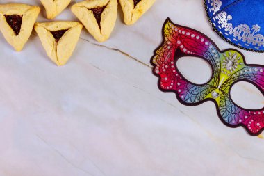 Purim background with mask, kippa and hamantaschen cookies.