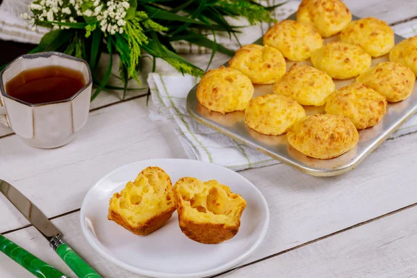 Cheese bread on plate and baking pan with tea. Brazilian traditional cuisine.